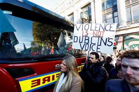 A man holds up 'Violence is not Dublin's voice' sign