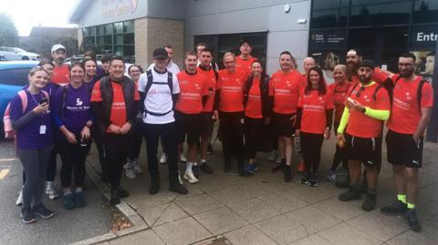 A group of people taking part in a charity walk pose for a photograph outside Aston Leisure Centre