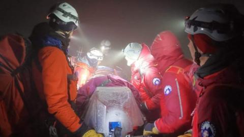 Mountain rescue team carries man in stretcher