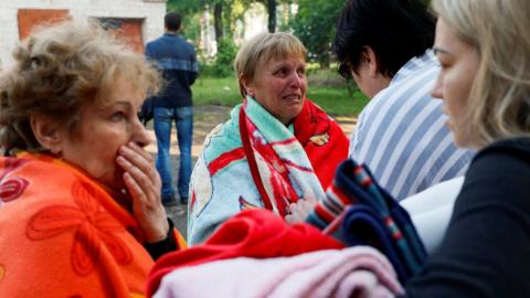 People react at a site of a residential building heavily damaged by a Russian missile strike