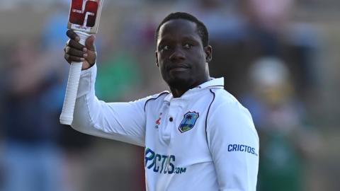 West Indies batter Nkrumah Bonner raises his bat to the crowd after hitting a century against England