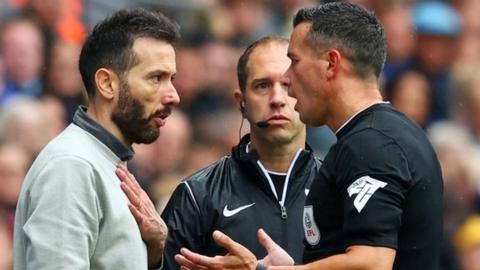 Referee Dean Whitestone speaks to West Brom boss Carlos Corberan