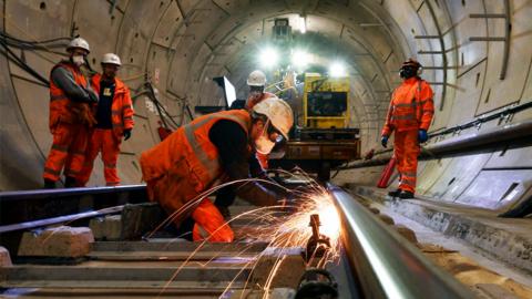 Construction workers on a section of train track inside a Crossrail tunnel, beneath Stepney in east London, in 2016