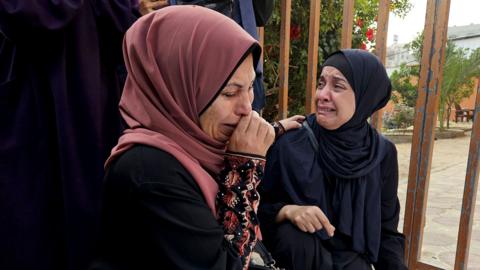 Two women cry in shock as they mourn victims of Israeli air strikes (not pictured) in Khan Younis on Thursday