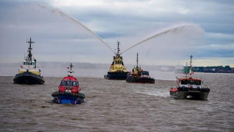 River tugs perform Fleur De Lis, (spraying of water from their fire cannons)