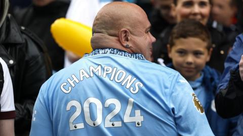 A Manchester City fan wearing a "Champions 2024" shirt before the trophy parade in Manchester