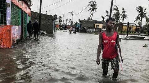 A man walks down a flooded road