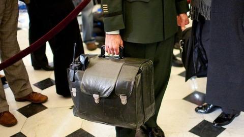 A military aide carries the nuclear football, with the United States' nuclear launch codes