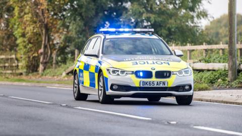 Generic images of a yellow and blue liveried Cheshire Police hatchback being driven on a road past a field.