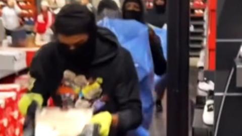 Video grab of people carrying goods in a Nike store with hoods and gloves