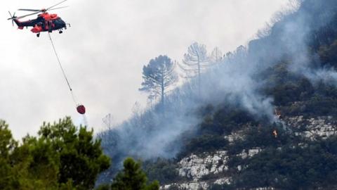 A helicopter drops water over a wildfire in Barx, in the eastern Spanish region of Valencia