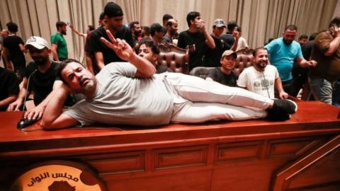 A supporter of the Iraqi cleric Moqtada al-Sadr lies on the desk of the speaker of the Iraqi parliament