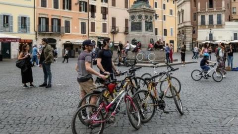 Cyclists stop in the Camp di Fiori square in central Rome, Italy. Photo: 16 May 2020