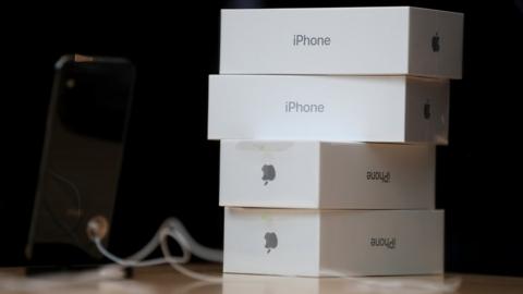 Boxes of the new iPhone X are stacked on top of one another next to a display item in an Apple Store.