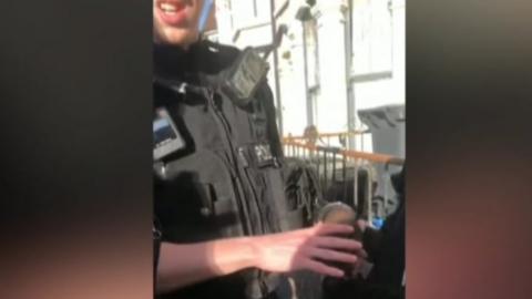 A young black boy in handcuffs with a white police officer