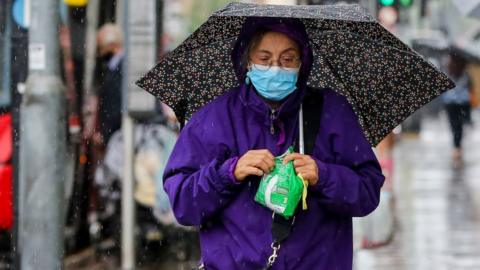 Woman walking down the street in the rain holding an umbrella