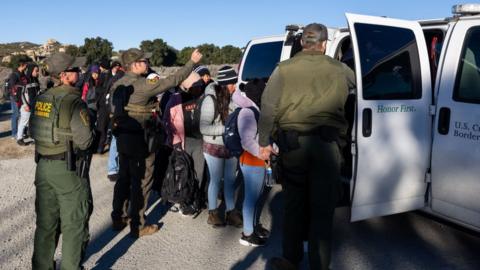 Detained migrants with Border Patrol officials