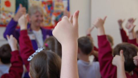 Children make thumbs up signs