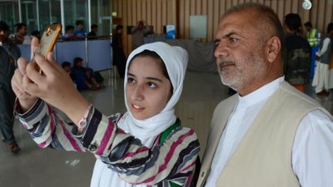 Afghan teenager Fatemah Qaderyan takes a photograph with her father at Herat airport on on July 13, 2017