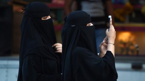 Women using mobile phones walk on Tahlia street in the Saudi capital Riyadh on September 24, 2017