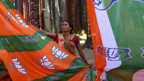 An Indian worker dries colourful materials dedicated to the Bhartiya Janta Party (BJP) and the Congress Party campaigns ahead of India"s general election, on the outskirts of Ahmedabad on March 11, 2019