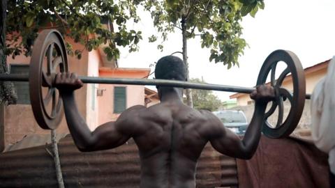 body builder with massive shoulder muscles lifts heavy weight outside