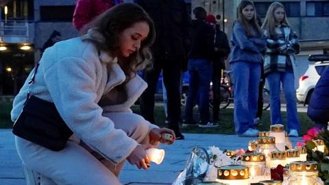 A woman lights a candle in Kongsberg, Norway,