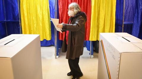 A woman votes at a polling station in Bucharest during parliamentary elections on 6 December 2020