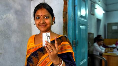 A female voter shows her ID and ink on her finger