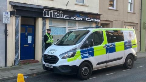 A police van and police officer standing outside Tri Exercise in Haverfordwest