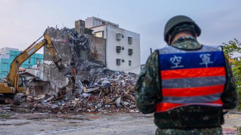 Rescue teams demolish a collapsed building following the earthquake