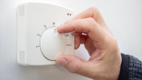 A hand adjusting a thermostat