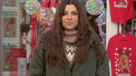 Influencer Gemma wearing a green parka and Fairisle jumper in front of a Christmas shop