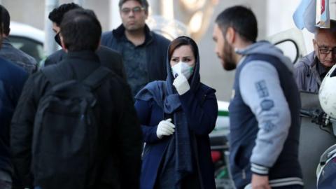 An Iranian woman wearing face mask walks on a street of Tehran, Iran, 9 March 2020.