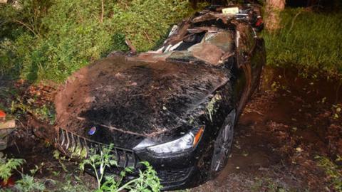 A Maserati crashed into a tree the front window screen is broken