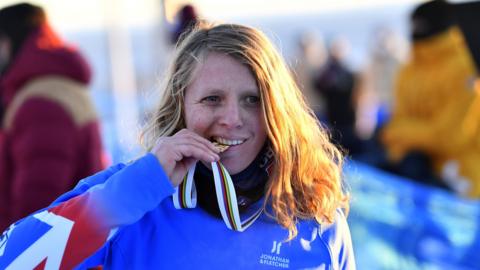 Charlotte Bankes poses with her World Championship gold medal between her teeth in 2021