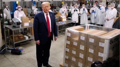 Employees take photos as President Trump speaks during a tour of a US factory.