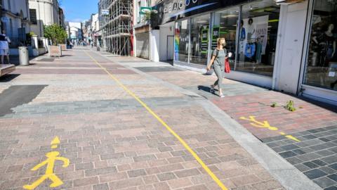 A woman walking through Merthyr Tydfil while wearing a facemask