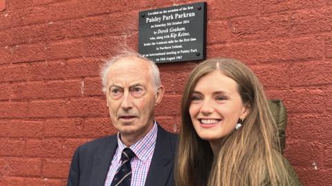 Derek Graham pictured with granddaughter Ruth McConnell as the unveiling of the plaque to commemorate his sub four-minute mile run at Belfast's Paisley Park in 1967 when he finished second to Kenyan great Kip Keino