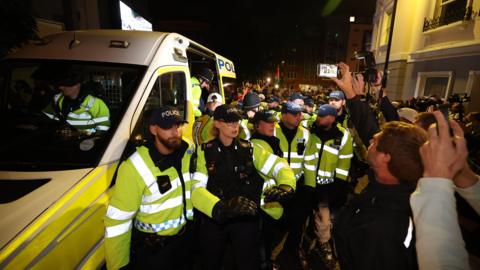 Police officers form a line in front of a police van in Brighton