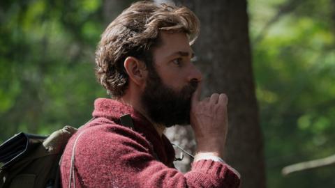 John Krasinski hushing with fingertip in still from the film