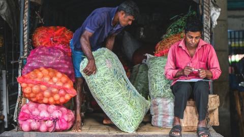 A labourer carries a sack of green beans at a market in Colombo.