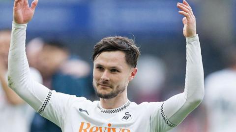 Liam Cullen, while playing for Swansea City, holding his arms up while looking on towards the supporters