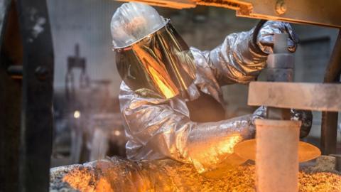 A metal worker wearing face protection