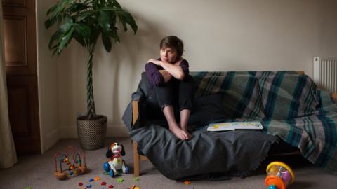 a sad woman sits on a sofa