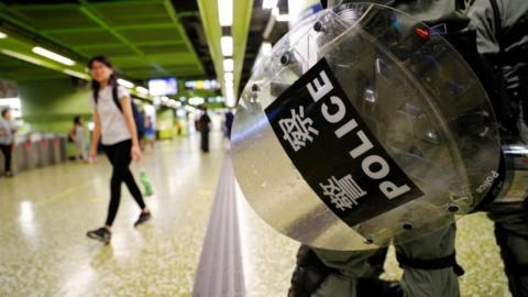 A riot police holds a shield inside a railway station, Hong Kong