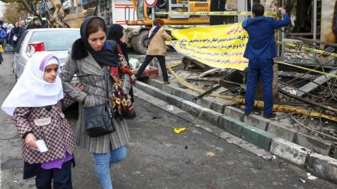 Woman and child walk past debris following anti-government protests in Tehran (20/11/19)