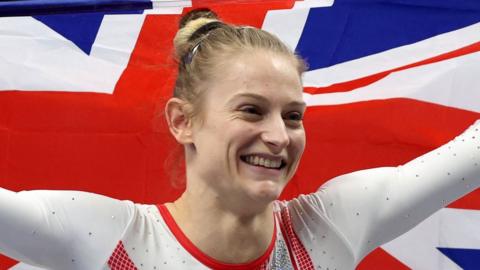 Bryony Page smiles whilst holding the Union Jack flag in celebration