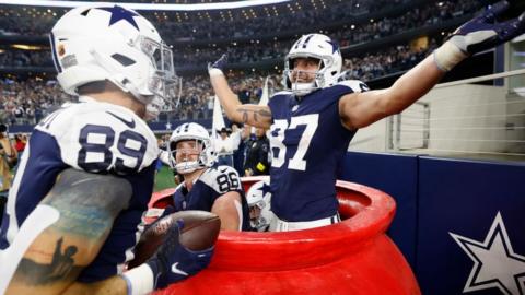 The Dallas Cowboys celebrate in the Salvation Army kettle