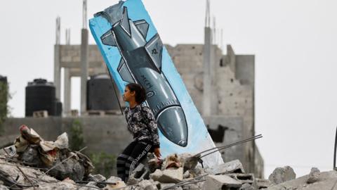 A Palestinian girl sits on the remains of a building in Deir al-Balah destroyed in the recent fighting between Israel and Palestinian militants in Gaza (8 June 2023)